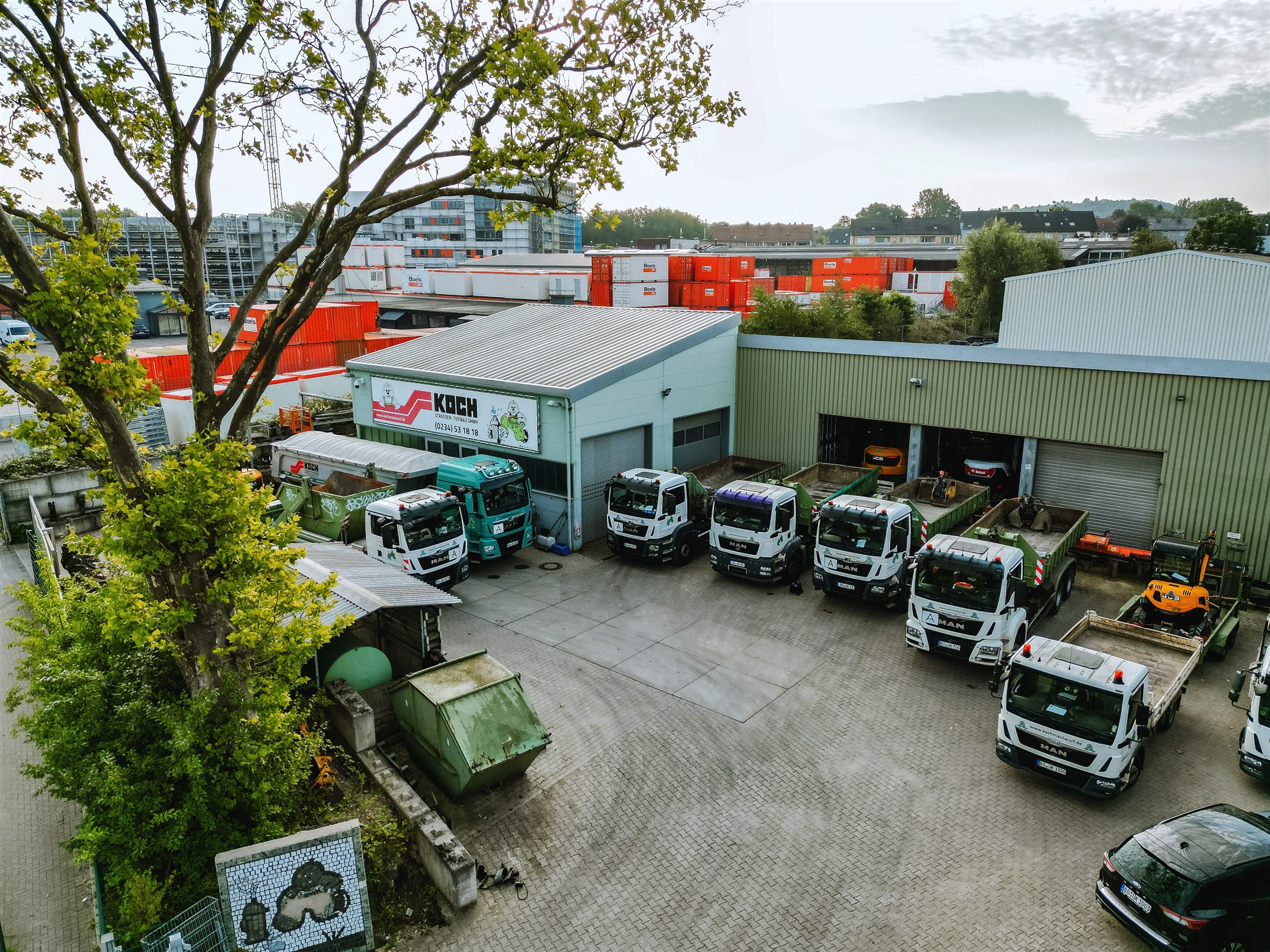Luftaufnahme des Firmenhofs der Josef Koch GmbH mit Fuhrpark und Betriebshalle